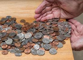 mãos pegando troco solto dos eua com moedas mistas na mesa de madeira foto