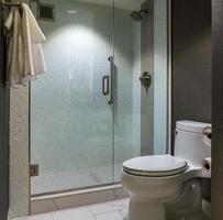 banheiro de hotel moderno com chuveiro e vaso sanitário de parede de vidro foto