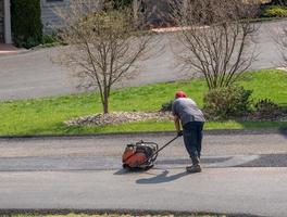 trabalhador aplicando asfalto extra para reparar rua de asfalto foto