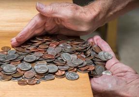 mãos pegando troco solto dos eua com moedas mistas na mesa de madeira foto