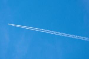 contrail atrás de um forro de jato de aeronaves em um dia de céu azul claro foto