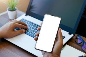 telefone de espaço de cópia de maquete, a mão do homem segurando o smartphone com tela de cópia branca em branco para sua publicidade e mensagem ou conteúdo de informação, móvel na mesa do café. foto