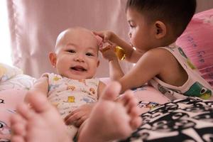 o bebê irmã asiática brincando com seu bebê menino na sala de estar. foto