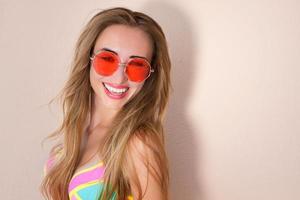 close-up de menina feliz em óculos de sol rosa isolados. férias de verão e fim de semana divertido. conceito de verão. jovem sorridente em maiô de moda. foco seletivo. roupa de verão de praia. espaço de cópia foto