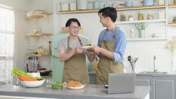 jovem casal gay sorridente cozinhando juntos na cozinha em casa, lgbtq e conceito de diversidade. foto
