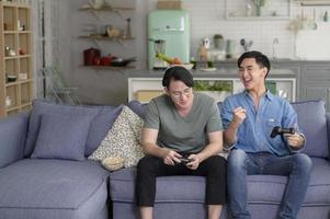 jovem casal gay sorridente jogando videogame na sala de estar em casa, lgbtq e diversidade foto