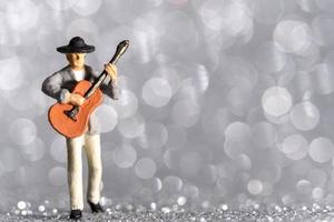 músico em miniatura com guitarra em bokeh de fundo foto