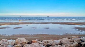 paisagem com mar e praia tem primeiro plano de pedra rochosa foto