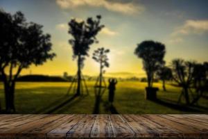 mesa de madeira e borrão de beleza em um dia de pôr do sol em um campo com céu e montanhas ao fundo. foto