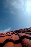 telhas vermelhas em um telhado de casa sob o céu azul