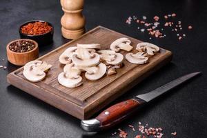 lindos jovens champignons brancos rasgados em fatias em um fundo escuro de concreto foto