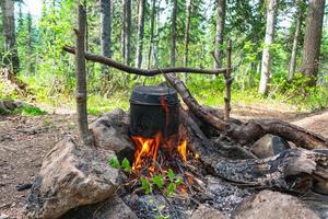 fogueira na floresta onde a comida é cozida em uma panela foto