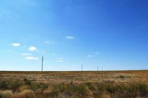 estepe em um dia ensolarado e quente e linhas de energia foto