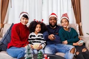 família afro-americana no tema de natal. família feliz se diverte sentados juntos no sofá em casa. foto