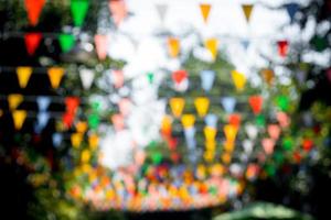 muitas bandeiras triangulares multicoloridas adornam o jardim desfocado. foto