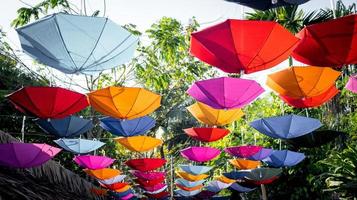 muitos guarda-chuvas de cores diferentes estão pendurados no jardim, dando às pessoas uma sensação de relaxamento. foto