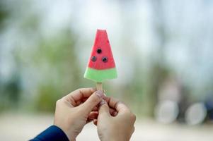 mão e sorvete vermelho comendo o conceito de sorvete com espaço de cópia foto