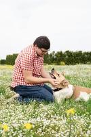 homem feliz brinca com cão pastor de raça mista na grama verde ao ar livre foto