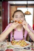adolescente comendo pizza de presunto e anana foto