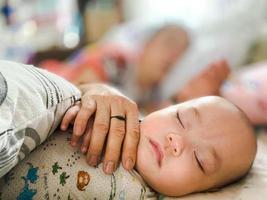 um bebê asiático dorme confortavelmente na mão da vovó. foto