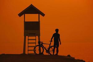 silhueta de um homem ciclista no pôr do sol na tailândia. foto