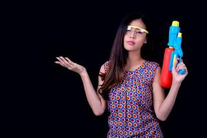 uma linda mulher asiática mostra um gesto enquanto segura uma pistola de água de plástico durante o festival songkran foto