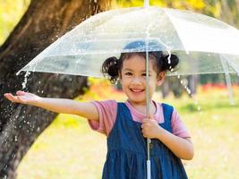 uma garotinha estava feliz em um guarda-chuva contra a chuva