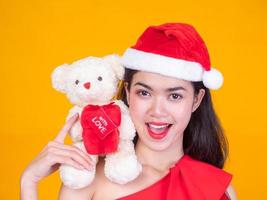 linda garota asiática em fantasia de papai noel vermelho e urso de amor no dia da celebração foto