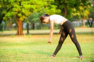 uma linda mulher asiática está se aquecendo, para tornar os músculos flexíveis antes de ir correr foto