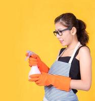 mulher bonita asiática segurando um spray de garrafa para limpar o dispositivo e sorrindo alegremente para limpar a casa foto