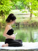 lindas mulheres grávidas sentam-se no parque, deixam as crianças na barriga ouvir música foto