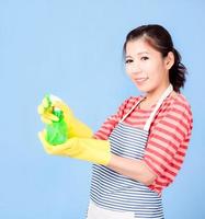 mulher bonita asiática segurando um spray de garrafa para limpar o dispositivo e sorrindo alegremente para limpar a casa foto