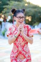 uma mulher asiática em um traje nacional chinês sorri com alegria ao receber uma bolsa de recompensa foto