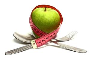 garfo de colher e maçã é amarrado por uma fita para medir a dieta foto