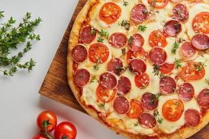 parte da pizza de calabresa italiana caseira quente com salame, mussarela na mesa branca foto