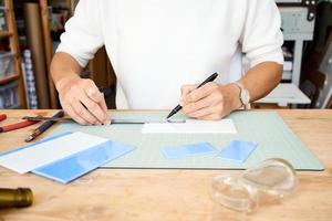 empresária sem rosto cortando vidro na oficina de artesãos. mulher de negócios desenha linha foto
