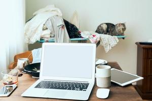 mesa freelance com laptop na bagunça no apartamento em casa. quarentena, auto-isolamento, sociofobia foto