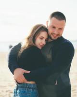 casal adulto jovem dançando na costa e se abraçando. bonito homem sorridente abraçando mulher foto