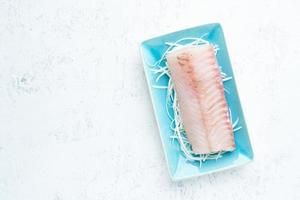 filé de peixe walleye branco cru em um prato azul sobre um fundo branco. vista superior, copie o espaço. foto