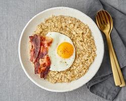 aveia, ovo frito e bacon frito. saudável café da manhã de alto teor calórico, fonte de energia. foto