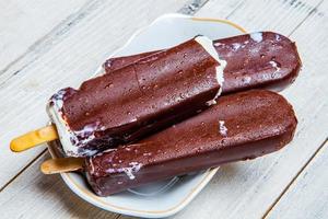 close-up de barra de chocolate de derretimento de sorvete. sorvete coberto com chocolate em fundo de madeira foto