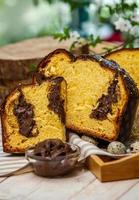 panetone feito em casa. pão doce italiano tradicional. panetone com uma fatia servida em uma mesa de madeira. foto