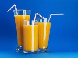 copos de suco de laranja em fundo azul com espaço de cópia foto