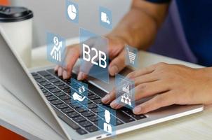 mão de homem usando negócios b2b de tela virtual portátil para ícones e símbolos de negócios. conceito de marketing de tecnologia de negócios. foto
