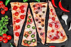 pizza com presunto, mussarela, tomate, azeitonas e pimenta em um fundo preto, vista superior