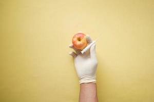 mão do médico segurando a maçã verde no fundo amarelo foto
