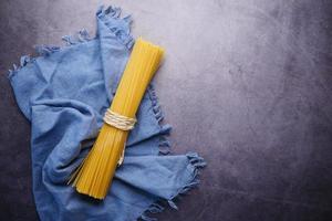 espaguete longo amarelo e uma toalha de mesa em fundo preto foto