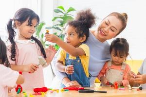 crianças brincando de brinquedos e jogos em casa com avós idosos positivos na sala de estar, meninas e meninos passando um tempo feliz com a vovó foto