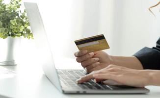 mulher asiática verificando os detalhes do pedido on-line no computador e usa as informações do cartão de crédito inseridas no computador. foto