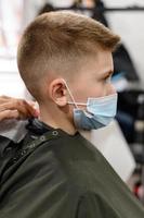 estudante em uma barbearia durante uma pandemia, corte de cabelo elegante para bebê. foto